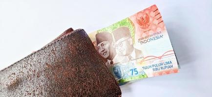 eine 75.000-Rupiah-Banknote von der Bank Indonesien unter der dunkelorangenen Brieftasche mit grauem Hintergrund. ausgestellt während der 75. nationalen Unabhängigkeit von Indonesien am 17. August 2020, Zeitraum 1945-2020. foto