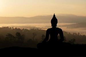 Schattenbildbuddha auf goldenem Sonnenunterganghintergrund. foto