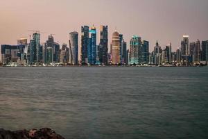 doha katar skyline bei nacht, die wolkenkratzerlichter zeigen, die sich im arabischen golf spiegeln foto