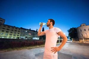 Mann trinkt Wasser nach dem Laufen foto