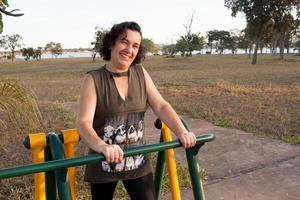 Reife Frau, die versucht, in einem Outdoor-Fitnesspark in Form zu kommen foto
