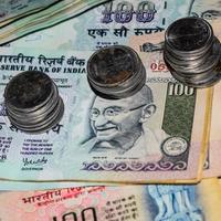 Seltene alte indische Bank-Rupie-Münzen, die auf Geldscheine fallen, herunterfallen indische Rupien-Münzen auf Hundert-Rupien-Scheine, indische Währungsmünzen fallen foto