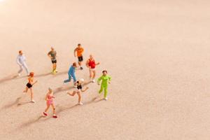 Miniaturmenschen, die beim Laufen in einer Gruppe am Strand trainieren foto