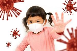 Kleines asiatisches Mädchen, das eine Maske trägt, um das Virus zu schützen und die Geste der Stopphände zu zeigen, um den Ausbruch des Koronavirus zu stoppen foto