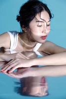 attraktives junges nasses Haar asiatisches Frauenmodell mit perfekter frischer Haut auf Unterwassersimulation der Beleuchtung Gesichtspflege Gesichtsbehandlung Kosmetologie plastische Chirurgie schönes Mädchenporträt im Studio foto