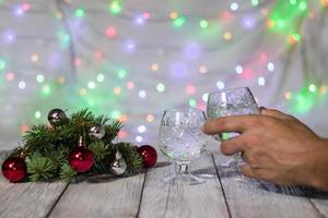 Hand hält ein Glas Champagner auf einem Tisch wieder Weihnachtslichterkette Bokeh im Hintergrund foto