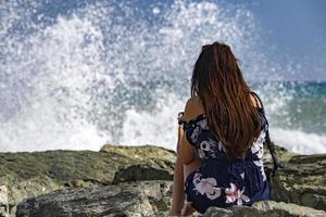 Frau beobachtet Seesturm an der Küste foto