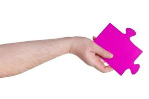 männliche hand, die großes rosa papierpuzzleteil hält foto