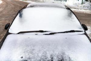 Vorderansicht des Autos, das im Winter von Schnee bedeckt ist foto