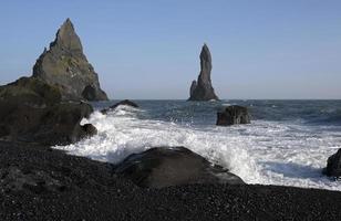 Wellen am schwarzen Strand von Reynisfjara, Island, mit Felsformationen im Hintergrund foto