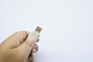 Die menschliche Hand auf dem gebrauchten Flash-Laufwerk ist ein weißes, kompaktes USB-Laufwerk foto