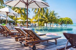 Sonnenschirme und Stühle rund um den Außenpool im Resorthotel für den Freizeit-Lifestyle im Urlaub. Luxus-Destination-Konzept, Lounge-Nahaufnahme unter Palmen, Entspannung, ruhige Atmosphäre