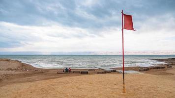 Rote Fahne am Strand des Toten Meeres im Winter foto