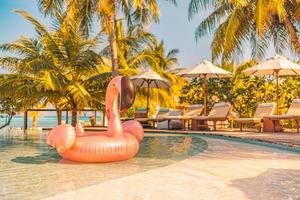 sommertourismus schwimmbad aufblasbarer rosa flamingo, luxusresorthotel am pool. glücklicher sonnenuntergang tropisches paradies insel infinity-pool meerblick. urlaub, urlaubsspaß landschaft. Freizeit entspannen foto