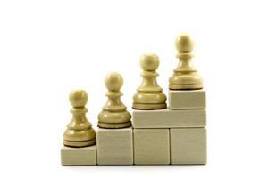 vier Schachfiguren stehen auf einer Leiter isoliert auf weißem Hintergrund. foto