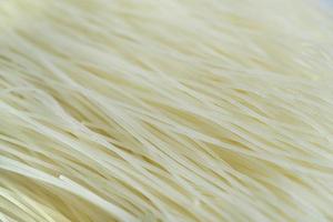 ungekochter und trockener Reisnudeln strukturierter Hintergrund, Lebensmittel-Makro-Nahaufnahme foto