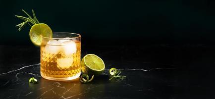 Alkoholischer oder alkoholfreier Cocktail mit Limette und Rosmarin auf dunklem Marmortisch foto