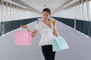 Porträt einer glücklich lächelnden Frau mit Einkaufstüten im Korridorweg. schöne Frau mit einer Papiertüte. foto