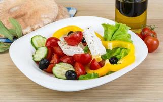 griechischer Salat auf dem Teller und Holzhintergrund foto