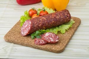 Salami auf Holzbrett und Holzhintergrund foto