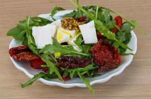 Salat mit getrockneten Tomaten auf dem Teller und Holzhintergrund foto