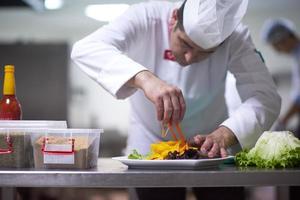 Küchenchef in der Hotelküche bereitet Speisen zu und dekoriert sie foto