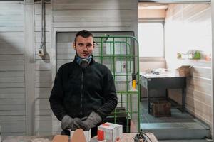 Ein Mann, der in einer Fabrik arbeitet, eine Gesichtsmaske und Handschuhe trägt und während einer Coronavirus-Pandemie arbeitet foto