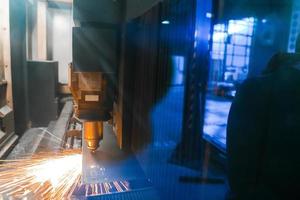 Funken fliegen aus Maschinenkopf für die Metallbearbeitung Lasermetall auf metallurgischem Anlagenhintergrund. herstellung fertiger teile für das konzept der automobilproduktion foto