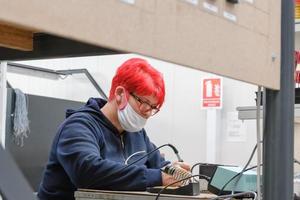 industriearbeiter, die aufgrund einer coronavirus-pandemie eine gesichtsmaske tragen, löten kabel von fabrikproduktionsanlagen foto