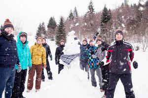 gruppenporträt von jungen leuten, die mit schneemann posieren foto