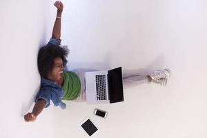 afroamerikanerfrau, die auf dem boden sitzt, mit laptop-draufsicht foto