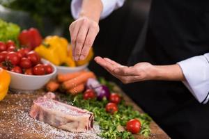 koch, der salz auf eine saftige scheibe rohes steak legt foto