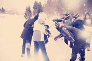 Gruppe junger Leute, die einen Schneemann bauen foto