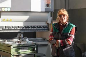 porträt einer frau, die vor einer cnc-maschine in schutzbrillen steht und in einer modernen metallproduktions- und verarbeitungsfabrik arbeitet foto