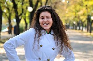 Brunette nette junge Frau, die draußen in der Natur lächelt foto