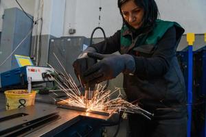 eine frau, die in der modernen metallerzeugungs- und -verarbeitungsindustrie arbeitet, schweißt das produkt und bereitet es für eine cnc-maschine vor foto