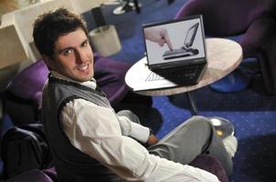glücklicher Mann sitzt und arbeitet am Laptop foto