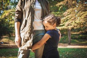 Trauriges kleines Mädchen, das Mutter im Park umarmt. foto