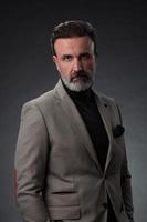 Porträt eines stilvollen, eleganten Senior-Geschäftsmanns mit Bart und lässiger Geschäftskleidung im Fotostudio isoliert auf dunklem Hintergrund, der mit den Händen gestikuliert foto