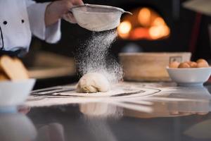 Küchenchef streut Mehl über frischen Pizzateig foto