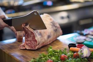 Koch schneidet ein großes Stück Rindfleisch foto