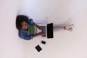 afroamerikanerfrau, die auf dem boden sitzt, mit laptop-draufsicht foto