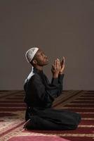 junger afrikanischer muslimischer Kerl, der betet foto