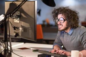 mann, der am computer im dunklen startbüro arbeitet foto