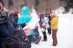 Jugendliche messen die Höhe des fertigen Schneemanns foto