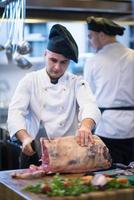 Koch schneidet ein großes Stück Rindfleisch foto