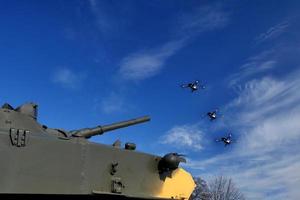 Der Panzer zielt mit einer Waffe auf die Drohne. Bekämpfung von Drohnen und Quadrocoptern foto