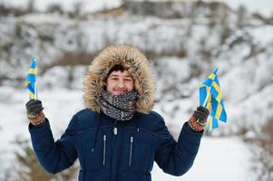 skandinavischer mann mit schwedenflagge in der schwedischen winterlandschaft. foto