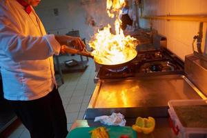 koch in der hotelküche bereitet essen mit feuer zu foto