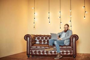 Lifestyle erfolgreicher Freiberufler mit Bart erreicht neues Ziel mit Laptop im Loft-Interieur foto